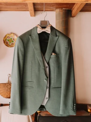 Traje del novio en tono verde colgado en un interior rústico Traje del novio en tono verde colgado en un interior rústico